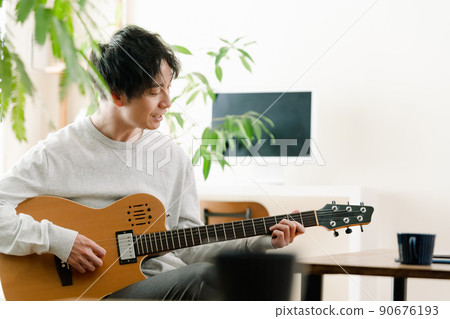 A man playing the guitar in the living room 90676193