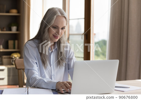 Senior businesswoman sit at desk typing e-mail use laptop 90676800