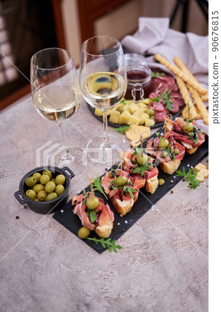 bruschetta with prosciutto ham and capers with traditional antipasto meat plate on background bruschetta with prosciutto ham and capers with traditional antipasto meat plate on background 90676815