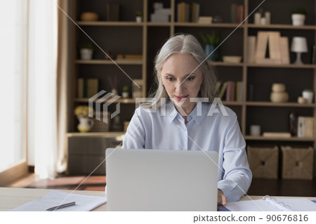 Middle-aged businesslady working on laptop seated at desk 90676816