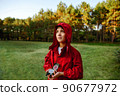 A boy in a red windbreaker against the backdrop of a forest with a compass in his hand. 90677972