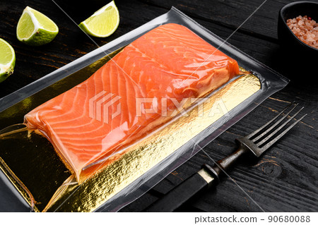 Salmon fillets in a vacuum package, with herbs, on black wooden table background Salmon fillets in a vacuum package, with herbs, on black wooden table background 90680088