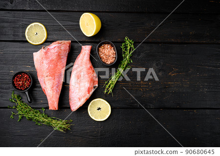 Raw red perch or sea bass fish, on black wooden table background, top view flat lay, with copy space for text Raw red perch or sea bass fish, on black wooden table background, top view flat lay, with copy space for text 90680645
