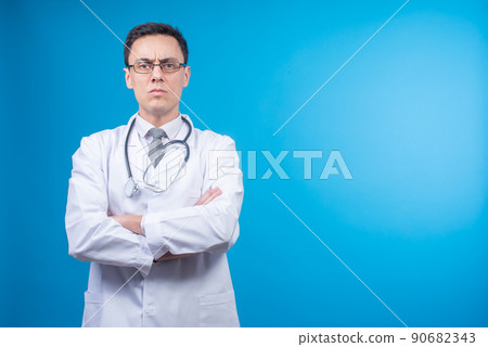 Strict doctor in glasses against blue backdrop Strict doctor in glasses against blue backdrop 90682343