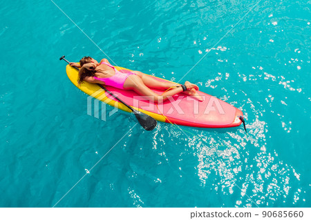 Attractive woman relaxing on Paddle board in blue sea. Sup surfing in ocean 90685660