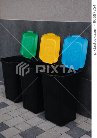Outdoors in the park is recycling bins different colours. Tree closed plastic bins is open. Green, yeallow and blue Outdoors in the park is recycling bins different colours. Tree closed plastic bins is open. Green, yeallow and blue 90687254