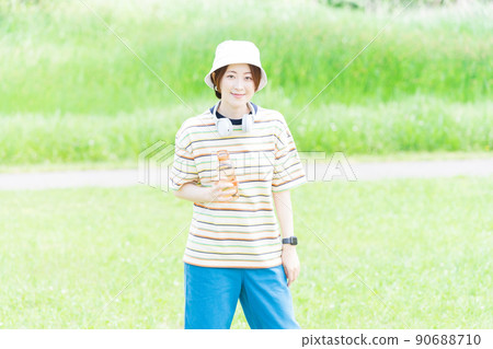 A woman taking a walk in the park with a water bottle 90688710