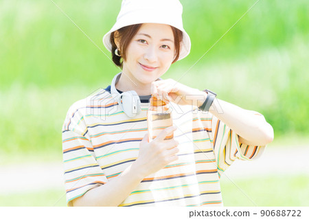 A woman taking a walk in the park with a water bottle A woman taking a walk in the park with a water bottle 90688722