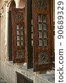 Windows with beautiful old wooden folding shutters on the walls of a adobe house, opening up in the courtyard   in the old city of Yazd 90689329