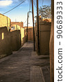 The old city of Yazd streets view in with adobe houses and oblique shadows on the walls of the houses against the blue sky. 90689333