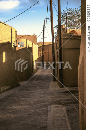 The old city of Yazd streets view in with adobe houses and oblique shadows on the walls of the houses against the blue sky. 90689333