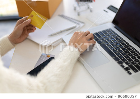 Businesswoman holding a credit card and using a laptop. Concept of online money transactions through laptop and online shopping. Businesswoman holding a credit card and using a laptop. Concept of online money transactions through laptop and online shopping. 90690357