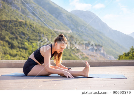 Young fitness woman doing stretching against stunning mountain view during her morning yoga routine 90690579