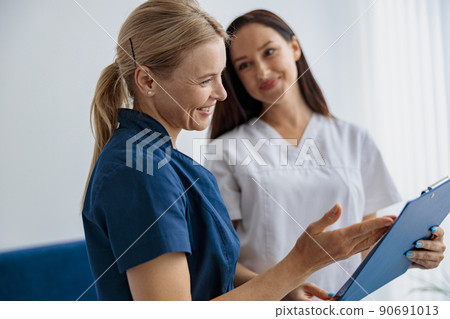 Doctor and nurse solve work issues standing near reception in clinic Doctor and nurse solve work issues standing near reception in clinic 90691013