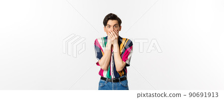 Shocked and startled man covering mouth, staring at camera speechless, standing over white background Shocked and startled man covering mouth, staring at camera speechless, standing over white background 90691913