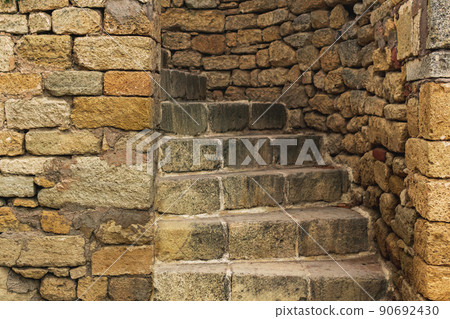 passage with a spiral staircase in an ancient stone wall 90692430