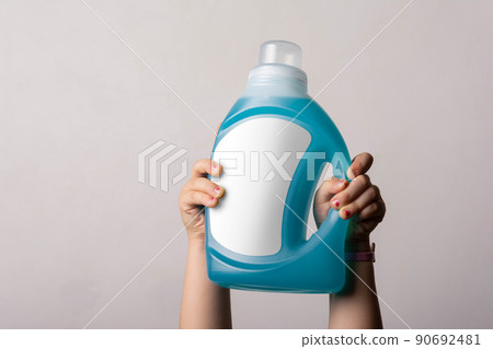 Cloth detergent liquid bottle at little girl hands in front of light gray background mock-up series 90692481
