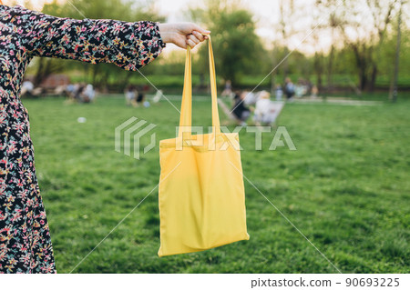 Happy young Woman with yellow cotton bag in her hands. Mockup and zero waste concept. Eco Nature Friendly Style. Environmental Conservation Recycling mock up Happy young Woman with yellow cotton bag in her hands. Mockup and zero waste concept. Eco Nature Friendly Style. Environmental Conservation Recycling mock up 90693225