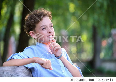 Young happy child boy relaxing sitting on bench in summer park. Positive kid enjoying summertime outdoors. Child wellbeing concept Young happy child boy relaxing sitting on bench in summer park. Positive kid enjoying summertime outdoors. Child wellbeing concept 90695614