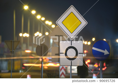 Roundabout road signs with blurred cars on city street traffic at night. Urban transportation concept Roundabout road signs with blurred cars on city street traffic at night. Urban transportation concept 90695726