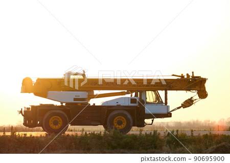 Heavy duty mobile lifting crane driving on intercity road at sunset Heavy duty mobile lifting crane driving on intercity road at sunset 90695900