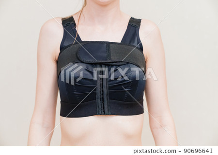 A young woman in black compression underwear after mammoplasty. 90696641
