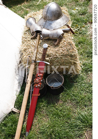 Reconsruction medieval age. Sword, helmet and gauntlet in field camp. Reconsruction medieval age. Sword, helmet and gauntlet in field camp. 90697720