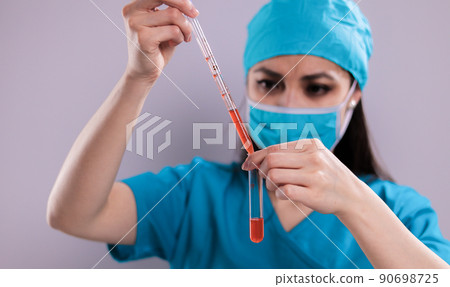 Female doctor examines a blood sample Female doctor examines a blood sample 90698725