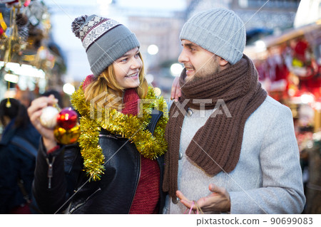Girl with boy choosing decorations at Christmas market Girl with boy choosing decorations at Christmas market 90699083