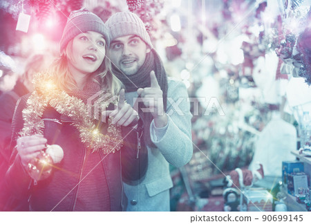 Positive young couple buying decoration at Christmas Fair 90699145