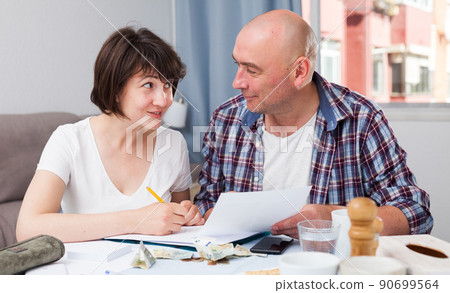 Husband and wife calculate income and expenses on smartphone 90699564