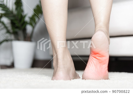 Asian woman standing feeling pain in her foot at home 90700822