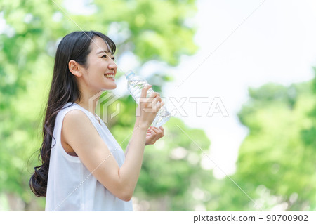A woman hydrating in the fresh green (profile) A woman hydrating in the fresh green (profile) 90700902