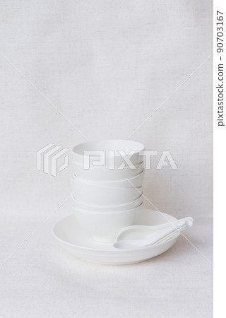 White ceramic bowl with spoon placed on white background 90703167