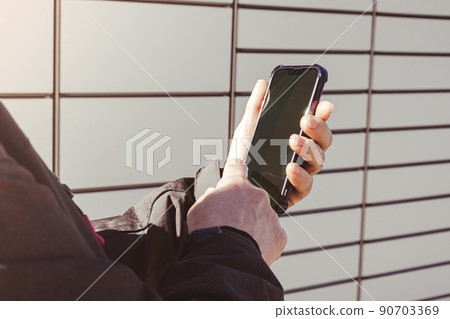 Female hand holding mobile phone next to Parcel locker Collecting parcel from shopping locker. Woman Skans QR Code on Mobile phone Self-service Locker Cell with Bar code Reader Modern Shipping and Female hand holding mobile phone next to Parcel locker Collecting parcel from shopping locker. Woman Skans QR Code on Mobile phone Self-service Locker Cell with Bar code Reader Modern Shipping and 90703369