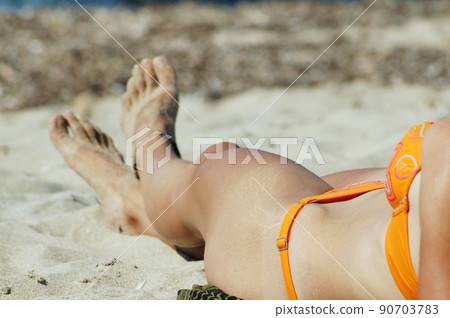 Young woman legs sunbathing on the beach 90703783