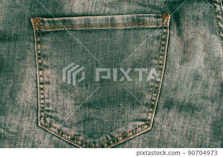 Rear pocket of gray-green jeans. Denim texture. Rubbed coarse fabric. Orange thread stitching. Casual wear. Modern trends. Multitask background with copy space for text and design elements. 90704973