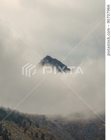 Soft focus. Darkness mountain background. Dramatic fog among giant rocky mountains. Ghostly atmospheric view to big cliff. Low clouds and beautiful rockies. Minimalist scenery mysterious place. 90707966