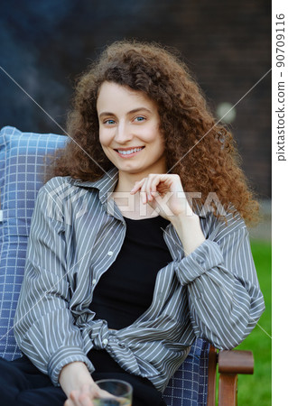 Outdoor portrait of smiling young woman with curly hair 90709116