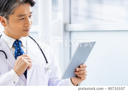 一名身穿白大褂的醫生站在設施內,手持平板電腦 一名身穿白大褂的醫生站在設施內,手持平板電腦 90710107