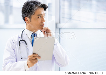 一名身穿白大褂的醫生站在設施內,手持平板電腦 一名身穿白大褂的醫生站在設施內,手持平板電腦 90710111