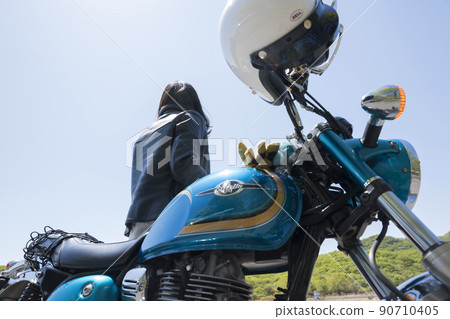 A young woman touring image with a motorcycle parked and looking at the scenery 90710405