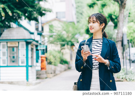 一個女人帶著智能手機在城市裡散步 90711180