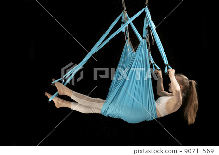 Side view portrait in full growth girl trains aerial gymnastics in sports hammock. Fly yoga. Anti-gravity yoga. Side view portrait in full growth girl trains aerial gymnastics in sports hammock. Fly yoga. Anti-gravity yoga. 90711569