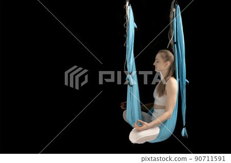 Girl meditates sitting in the lotus position in sports hammock. Fly Yoga. Anti-gravity yoga. Copy space. Girl meditates sitting in the lotus position in sports hammock. Fly Yoga. Anti-gravity yoga. Copy space. 90711591