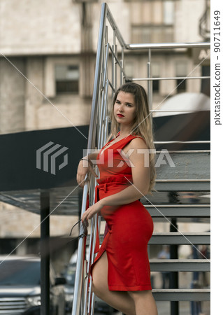 Portrait of sexy blonde in red summer dress with deep neckline. Young attractive business woman. 90711649