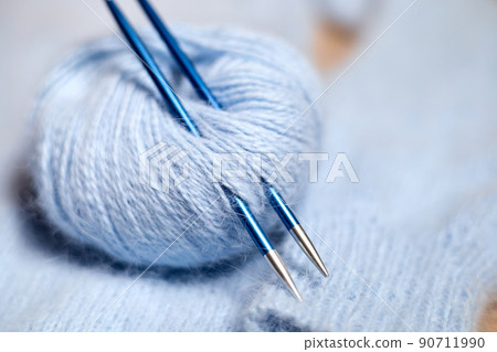 Blue knitted women's sweater with patterns, balls of thread and knitting needles Blue knitted women's sweater with patterns, balls of thread and knitting needles 90711990
