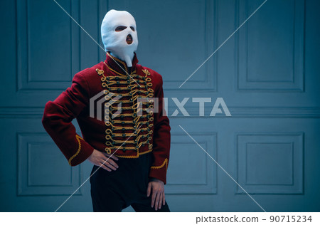 Young man, medieval hussar wearing white colors balaclava on dark blue background. Concept of comparison of eras, art, history. Creative collage. Young man, medieval hussar wearing white colors balaclava on dark blue background. Concept of comparison of eras, art, history. Creative collage. 90715234