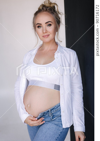 Portrait of pregnant woman in studio. Denim style. Beautiful future mother put her her hands on her belly Portrait of pregnant woman in studio. Denim style. Beautiful future mother put her her hands on her belly 90716172