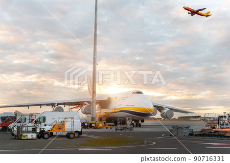 Schkeuditz, Germany - 29th May, 2022 - Large An-124-100 ukrainian Ruslan Antonov cargo jet parked on Leipzig Halle airport terminal tarmac apron for loading and service. DHL hub sunset background 90716331